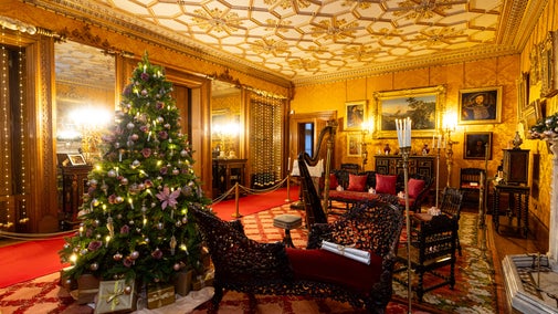 A Christmas tree with soft pink decorations stands in the golden Drawing Room